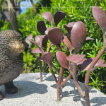 一株株銅葉舒展枝姿，在陽光下閃耀生命的光澤，鳥兒靜靜守望，為街道增添自然的詩意。